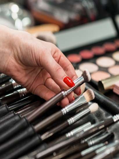 Mano tomando pinceles de maquillaje